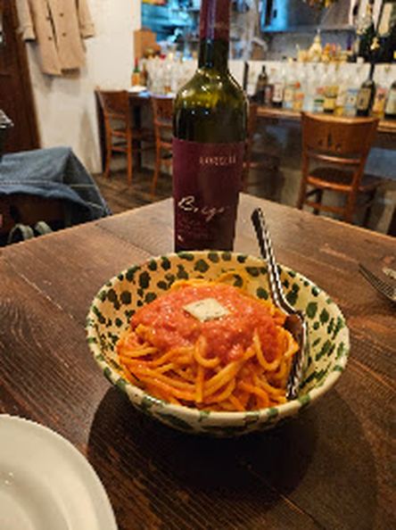 木のテーブルにワインボトルとトマトソースのパスタ